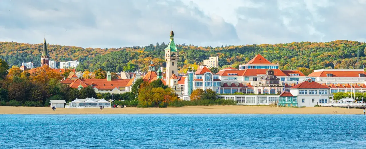 Sopot atrakcje: malowniczy widok na plażę, morze i zabytkowe budynki z wieżą widokową w jesiennej scenerii.