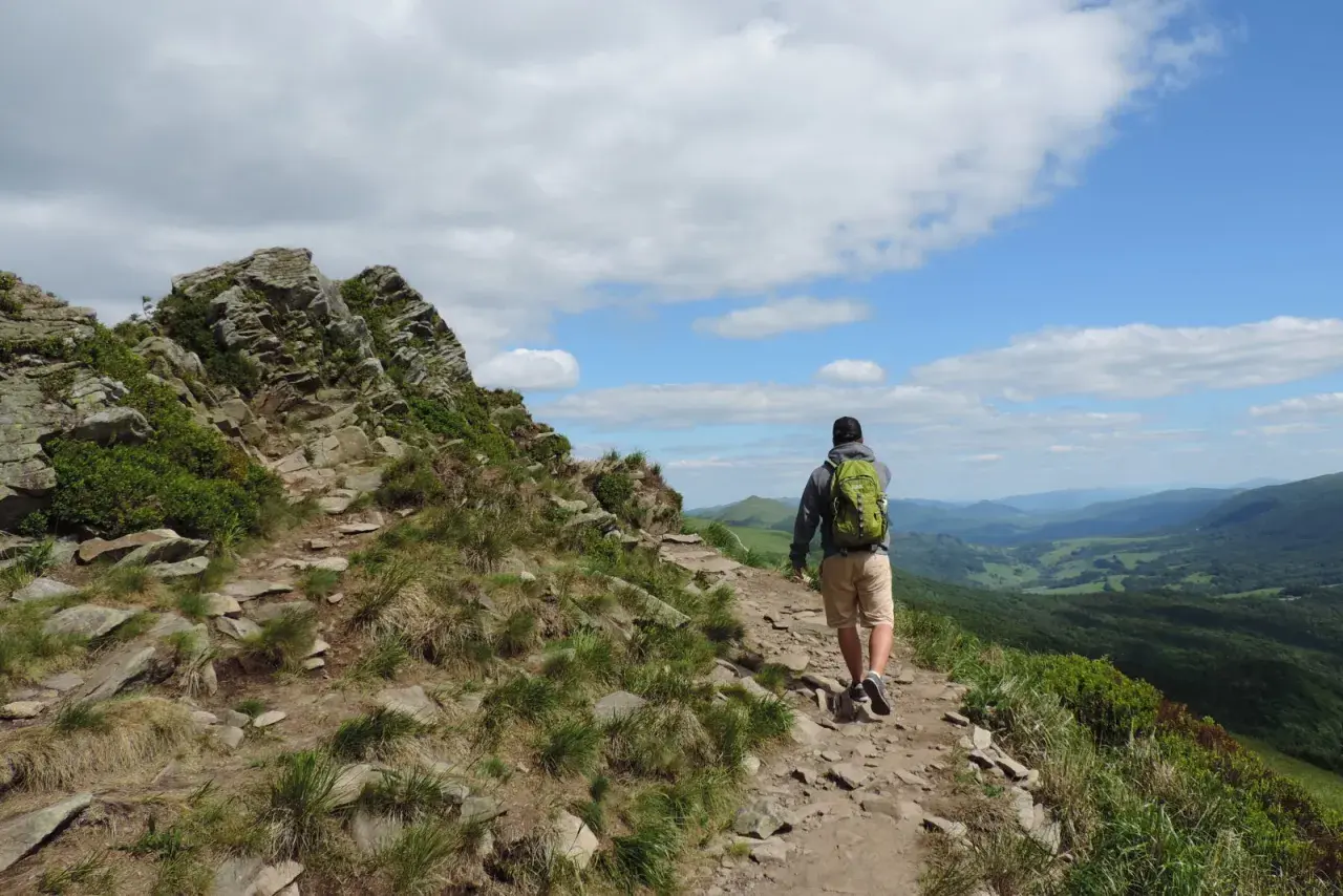Wędrowiec z plecakiem na skalistym szlaku. Piękne Bieszczady atrakcje czekają na odkrycie.