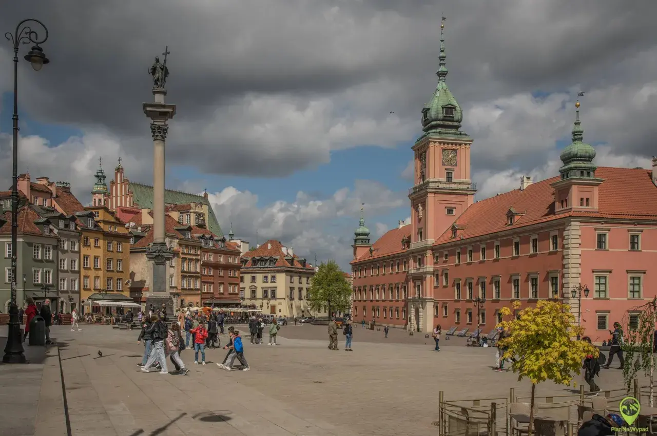 Kolumna Zygmunta i Zamek Królewski na placu w Warszawie. Wiele osób spaceruje, odkrywając warszawskie atrakcje.