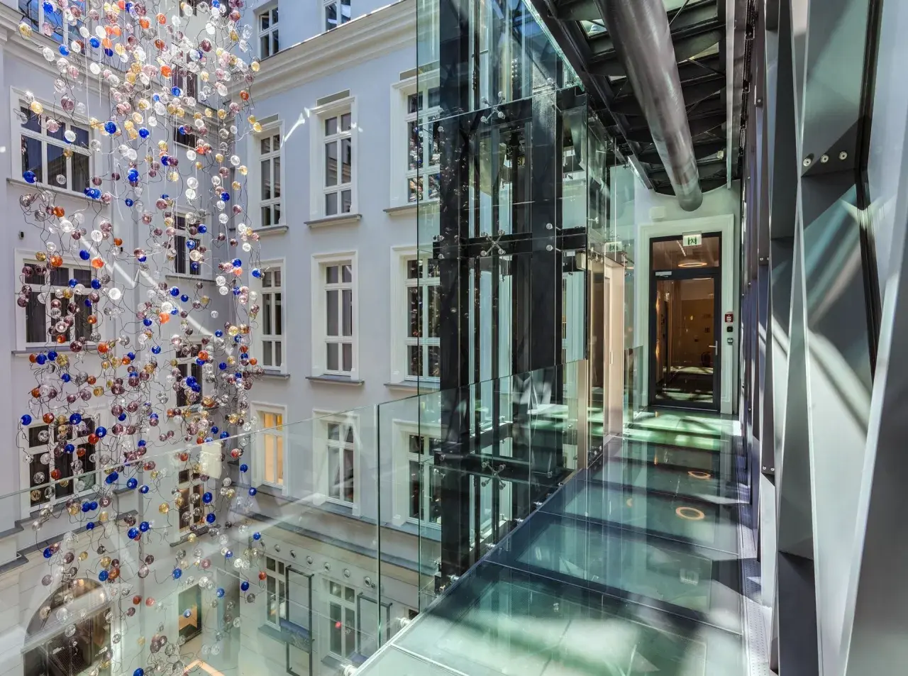 Nowoczesny dziedziniec hotelowy z instalacją szklanych kul i przeszklonymi korytarzami. Idealne miejsce na city break w Polsce.