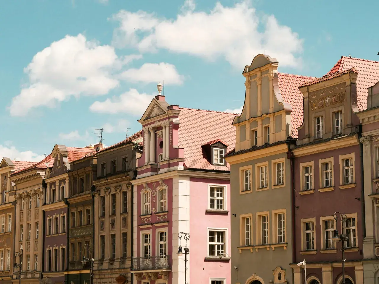 Kolorowe kamienice na Rynku w Poznaniu, piękne poznańskie zabytki pod błękitnym niebem z chmurami.