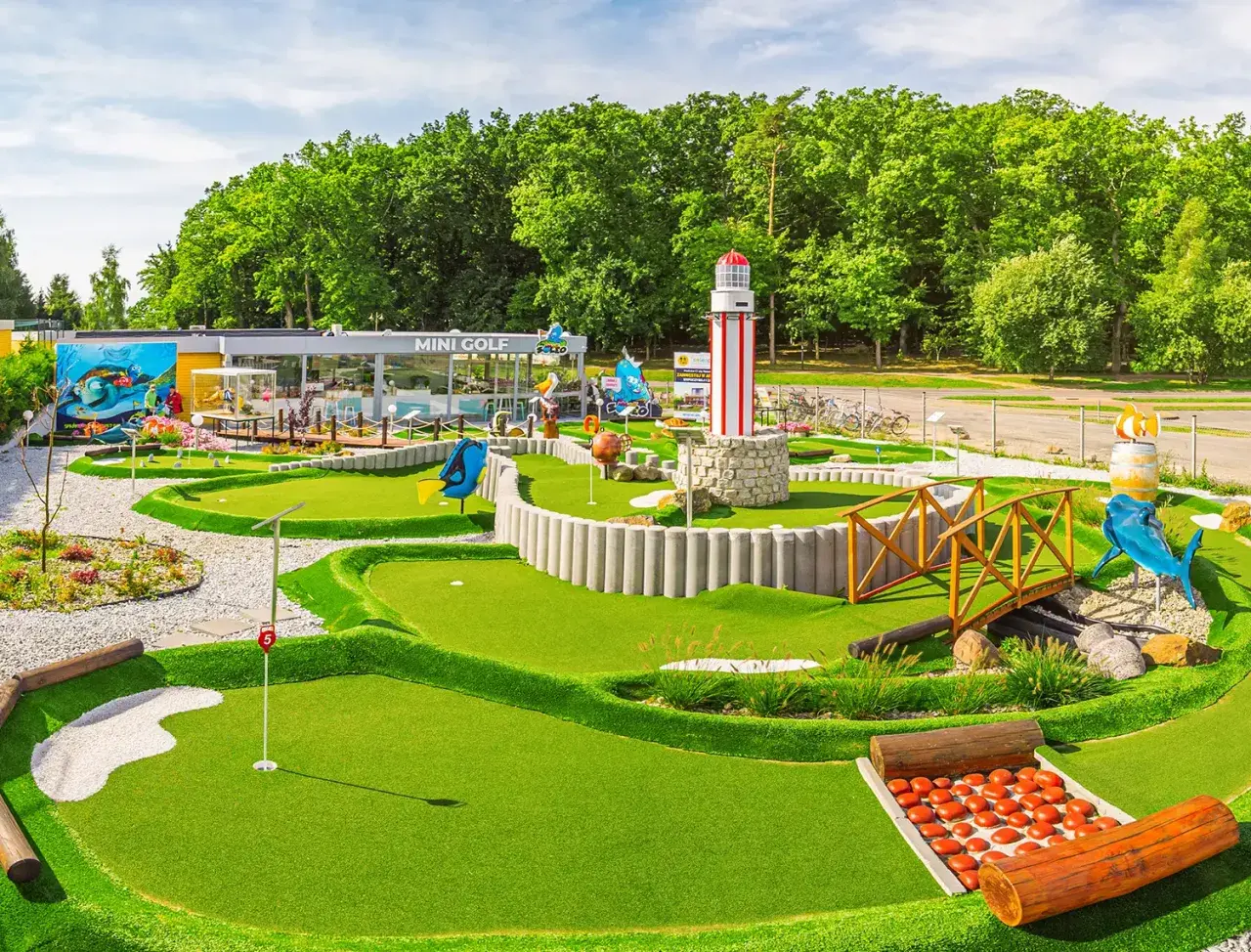 Mini golf w Rewalu to świetna zabawa! Wesołe dekoracje, w tym latarnia morska i rekin, zachęcają do gry.