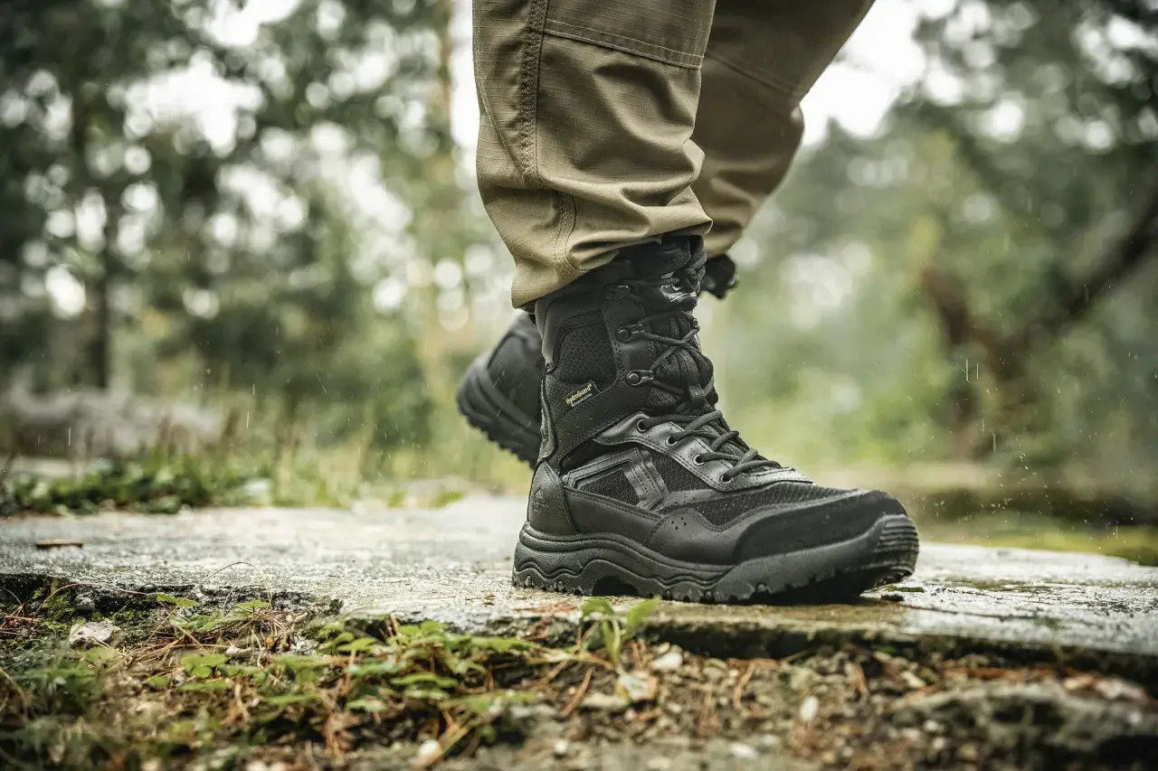 Czarne, wysokie buty trekkingowe z membraną HydroGuard na mokrej, kamienistej ścieżce. Idealne na trudne warunki.