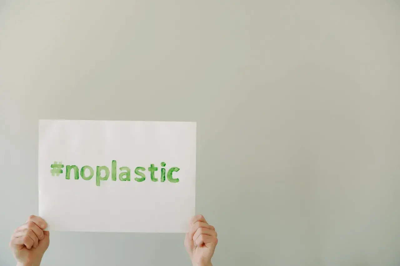 Ręce trzymają kartkę z napisem #noplastic. To apel o turystykę zrównoważoną i świadome wybory.