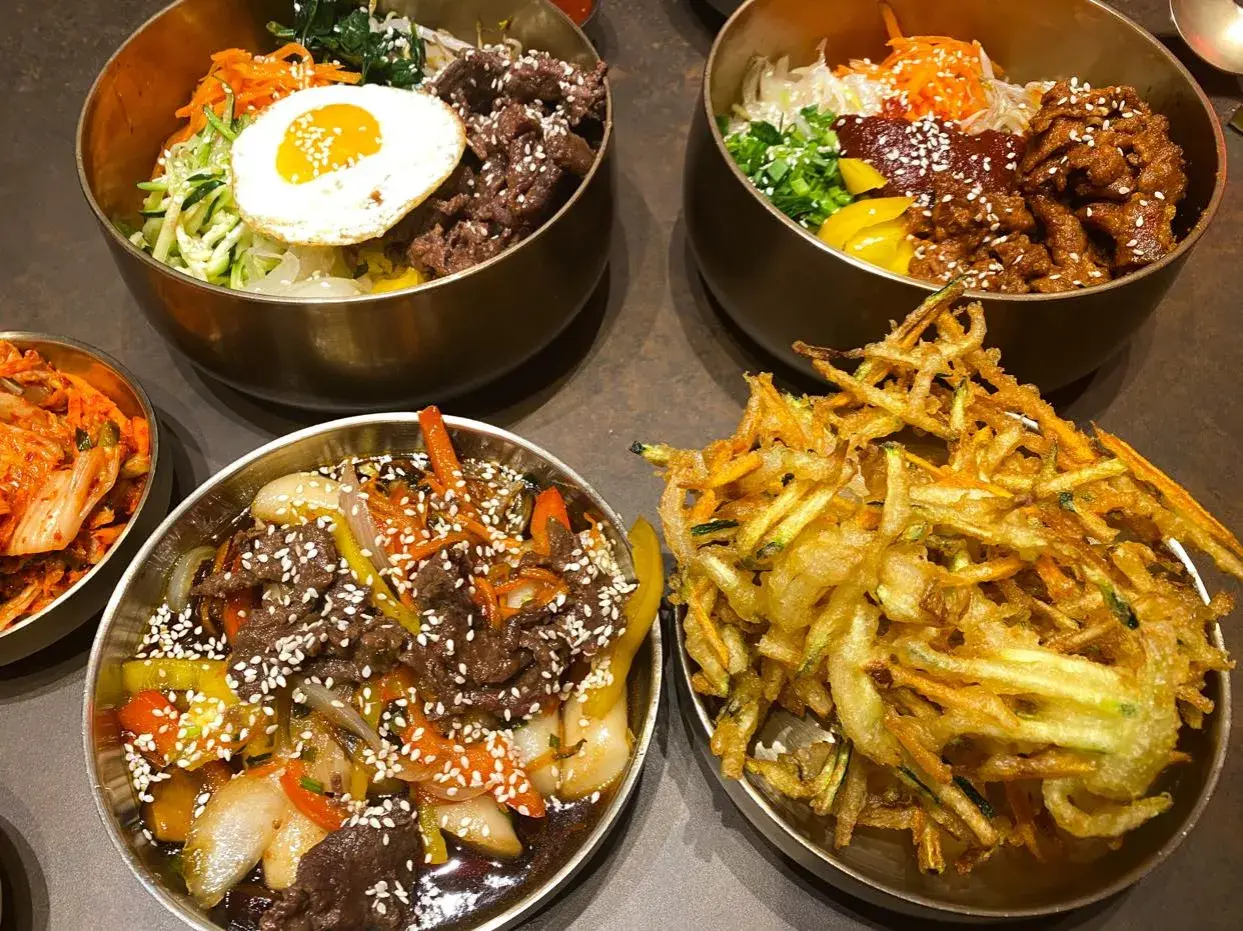 Pyszne dania kuchni koreańskiej, idealne dla polecanych restauracji w Poznaniu: bibimbap, bulgogi i chrupiące warzywa w cieście.