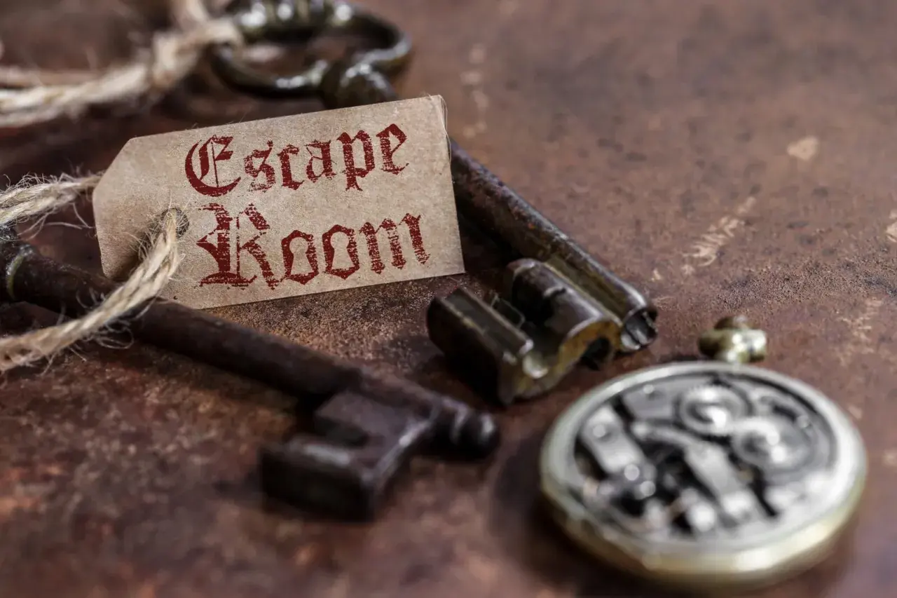 Stare klucze i przywieszka z napisem "Escape Room" na rustykalnym tle.