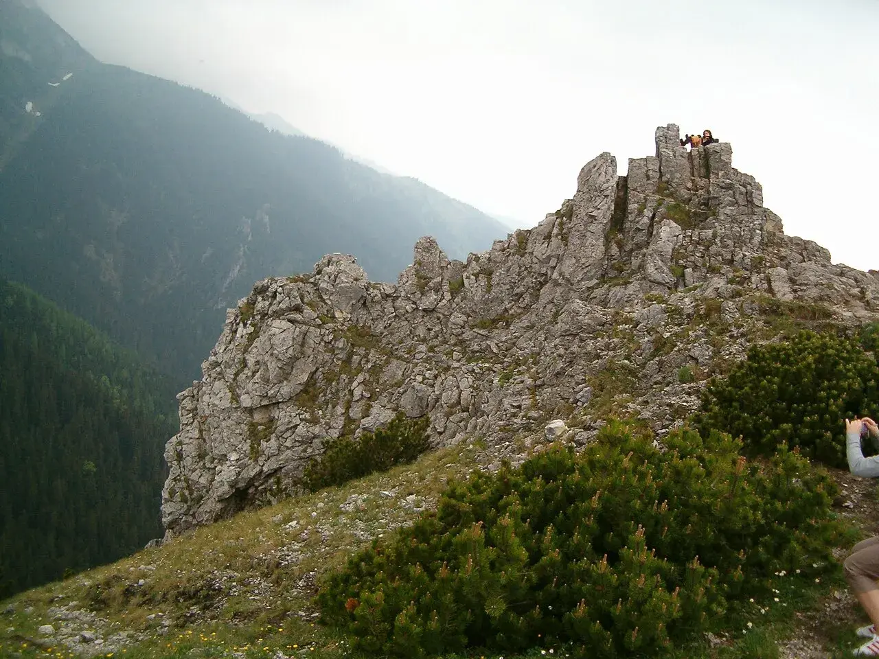 Sarnia góra wznosi się dumnie, skaliste szczyty przyciągają wzrok. Na górze widać ludzi podziwiających panoramę.