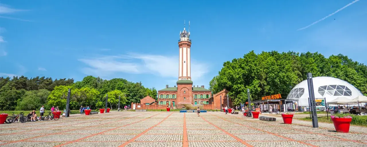 Latarnia morska w Niechorzu i plac z atrakcjami turystycznymi.
