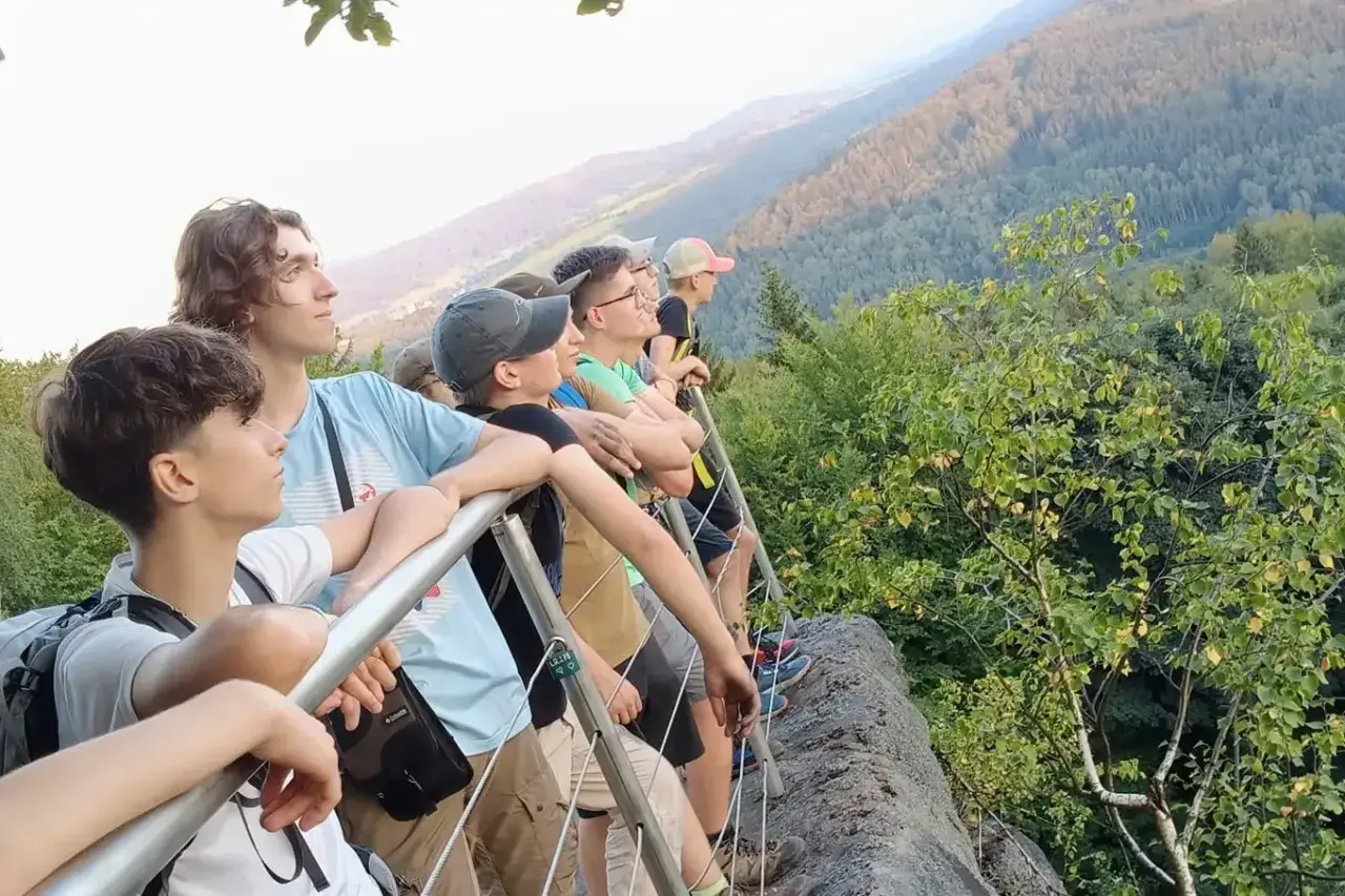 Grupa młodych ludzi podziwia widok z góry. To właśnie jest trekking – przygoda i odkrywanie piękna natury.