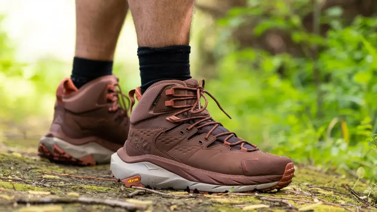Brązowe buty trekkingowe Hoka, model aku bellamont, na leśnej ścieżce.