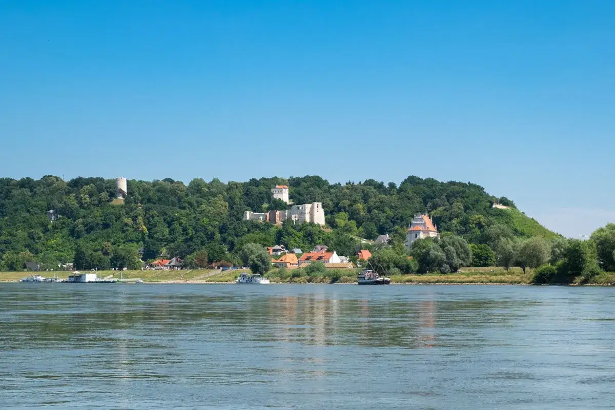 Widok na zamek i ruiny na wzgórzu w Kazimierzu Dolnym. Trasa widokowa wzdłuż Wisły z łodziami na wodzie.