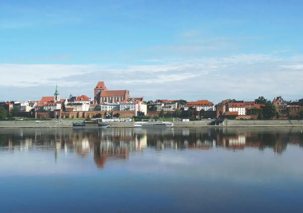 Panorama Torunia z katedrą i zamkiem krzyżackim, odbijająca się w Wiśle. Wspaniałe toruńskie atrakcje czekają na odkrycie!