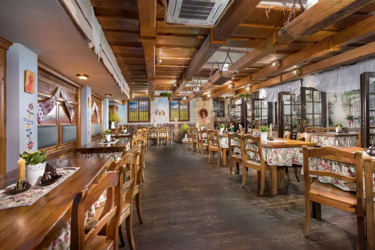 Przytulne wnętrze restauracji z drewnianymi stołami i krzesłami, idealne miejsce, gdzie zjeść w Krakowie.