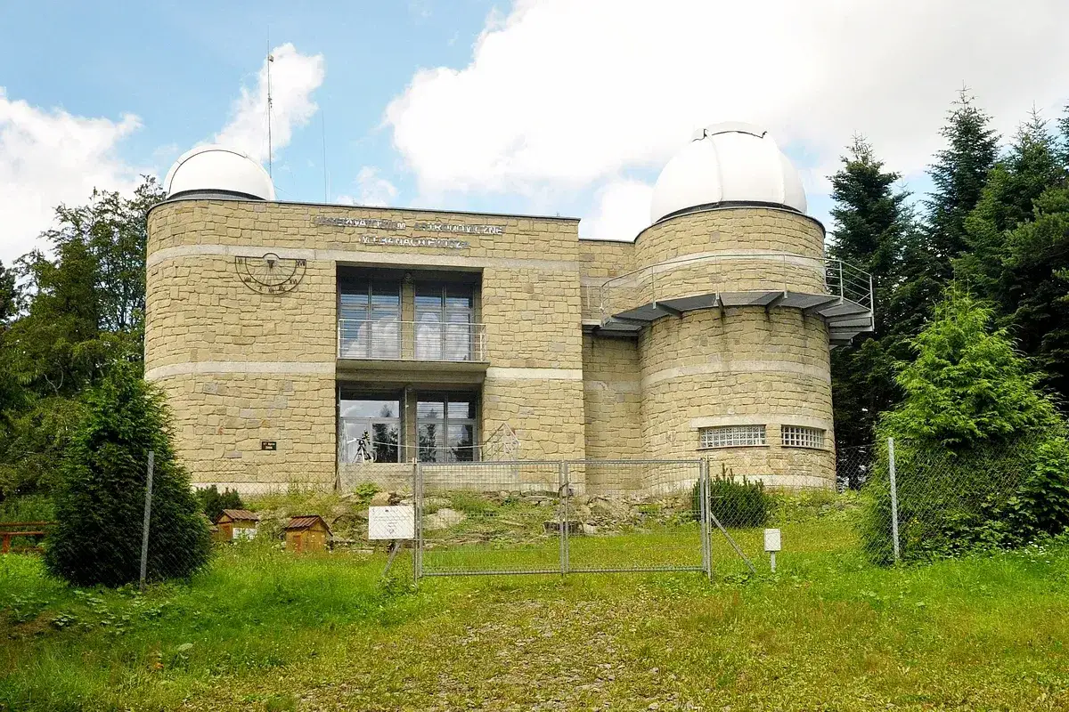 Obserwatorium astronomiczne im. Lubomira Szczyta z kopułami i zegarem słonecznym, otoczone zielenią.