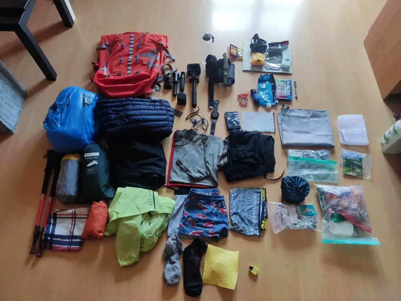 Sprzęt turystyczny, w tym plecak i odzież, gotowy na wyprawę. Wśr&oacute;d rzeczy widać polskie marki outdoorowe.