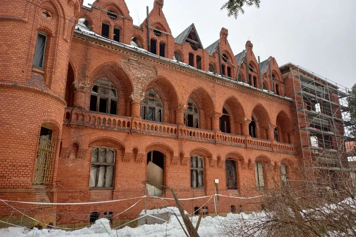 Sokołowsko atrakcje: zabytkowy sanatorium z cegły, z arkadowymi loggiami i rusztowaniami, w zimowej scenerii.