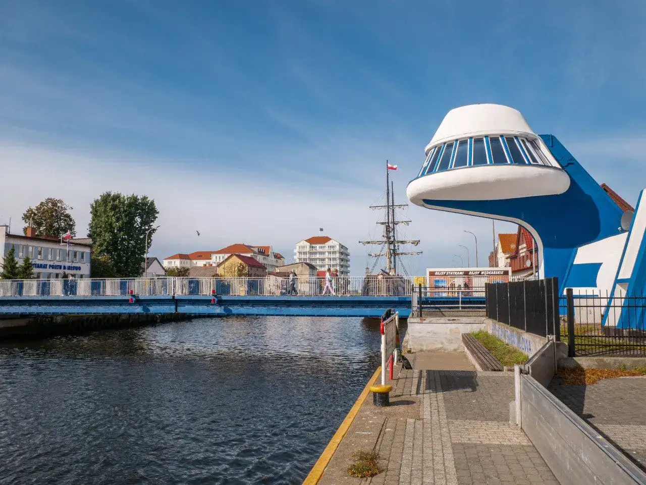 Niebieski most i futurystyczna budowla nad wodą w Dziwnowie. Widok na port i żaglowiec, ciekawe dziwnów atrakcje.