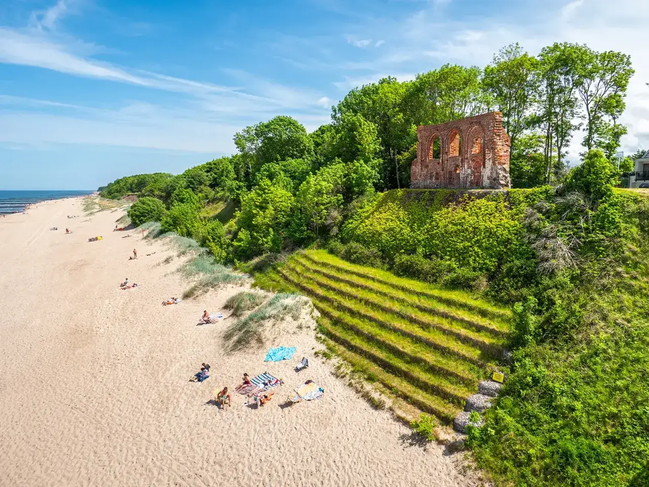 Piękna plaża z ruinami na klifie. Trzęsacz atrakcje przyciągają turystów, którzy odpoczywają na piasku i podziwiają widoki.
