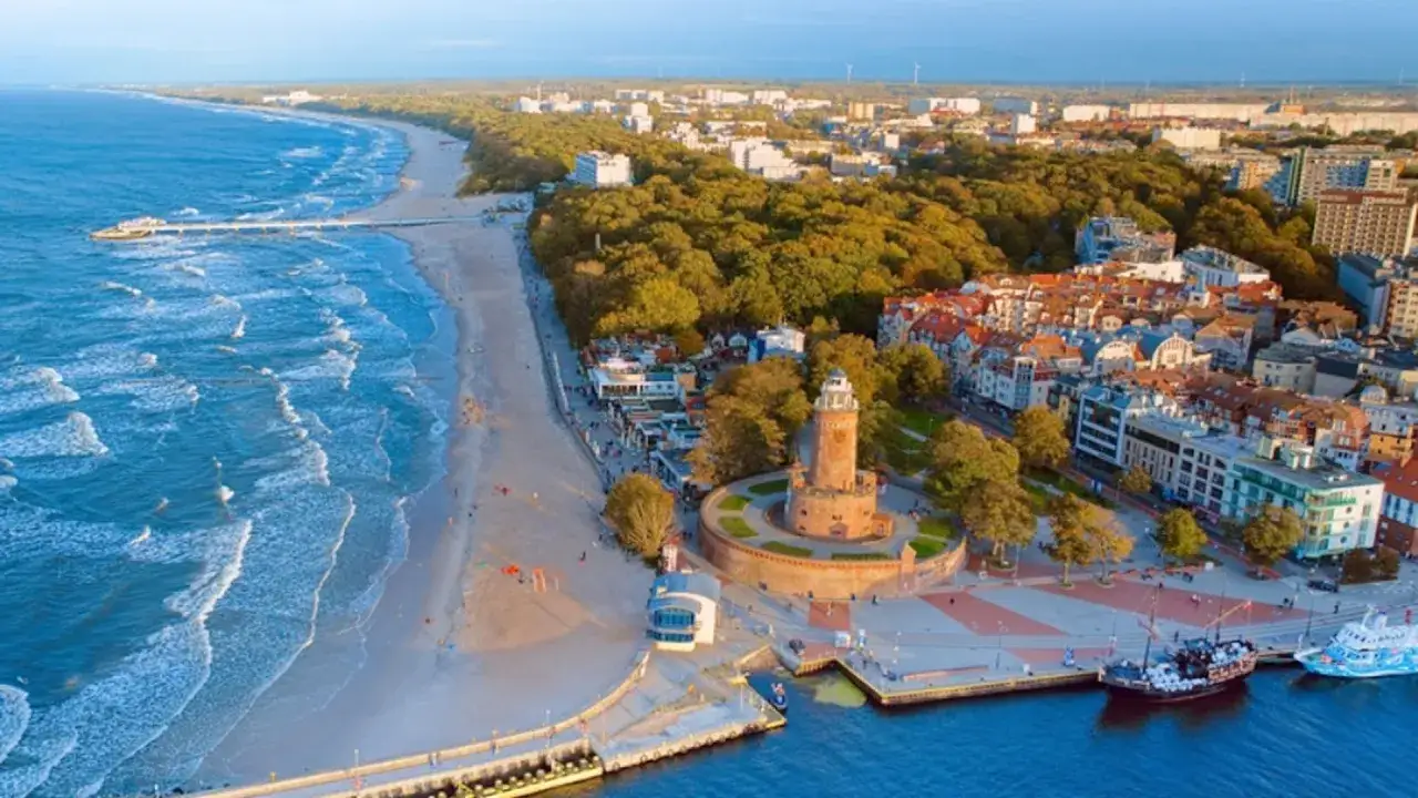 Widok na latarnię morską i plażę, jedno z najpiękniejszych plaż nad Bałtykiem. W tle miasto i las.