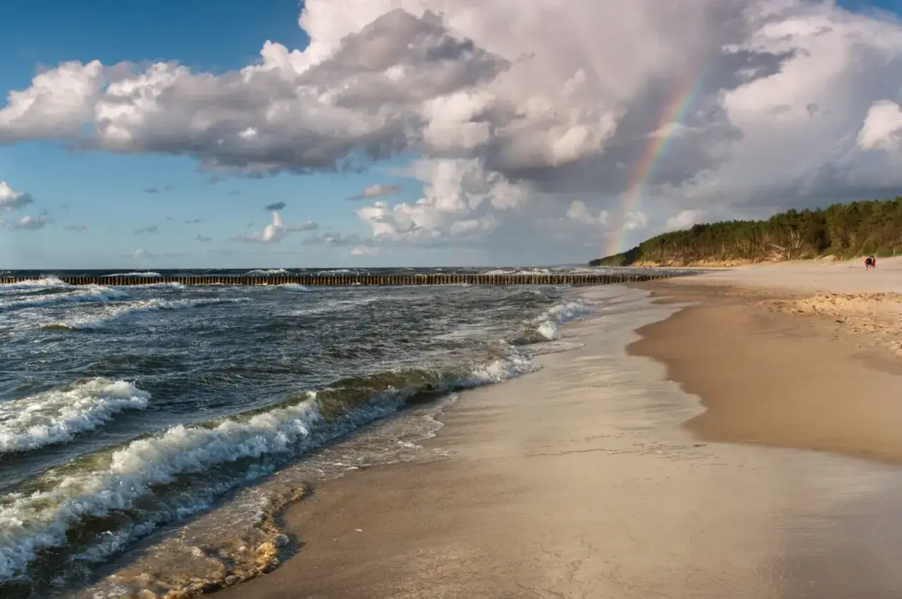 Piękny widok na plażę z tęczą po deszczu. Idealne miejsce na majówka dni wolne.